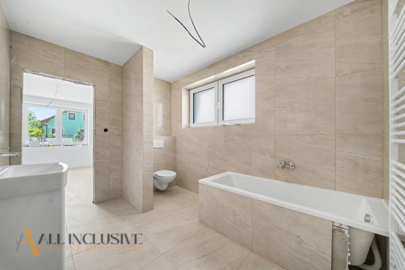 A bathroom in a family house with a bathtub, toilet, and tiled walls.
