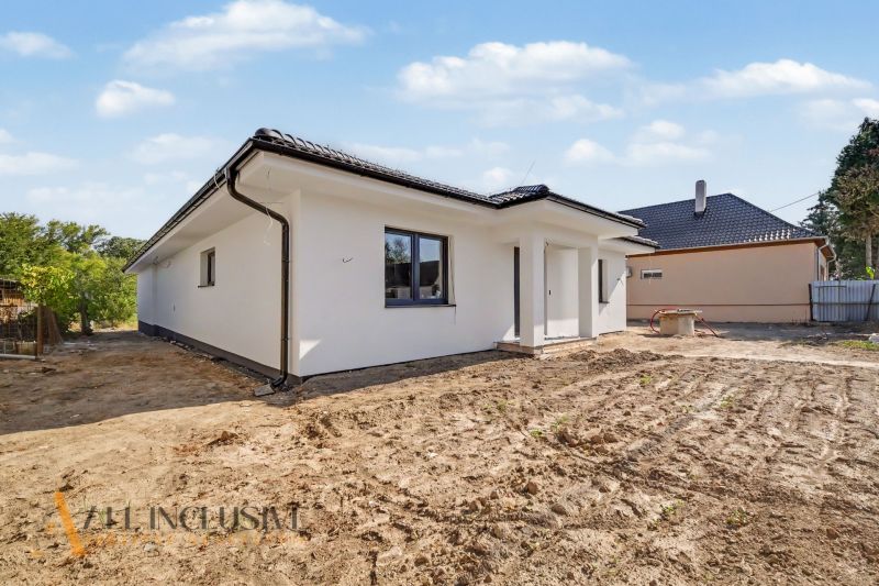Tomášik's family house with light plaster and a sloped roof, surroundings without landscaping.