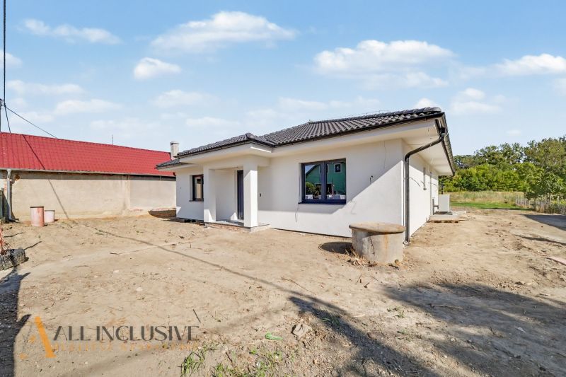 A family house in Tomášikovo with white plaster and a sloping black roof.
