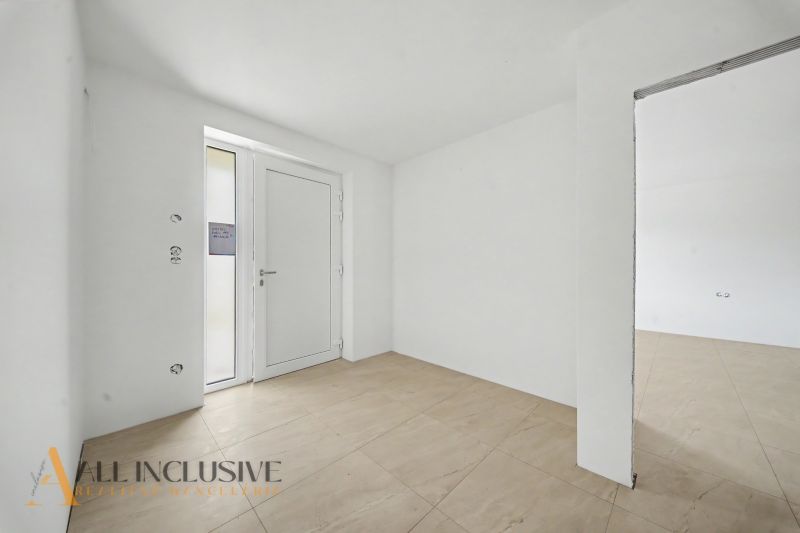 Entrance hall in a family house with white walls and wood-patterned tiles.