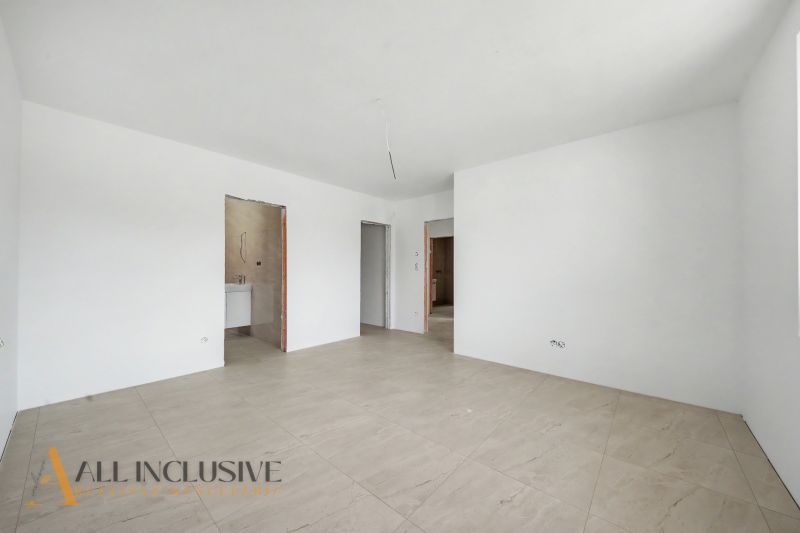 A spacious room with white walls and a wooden decor floor in a family house.