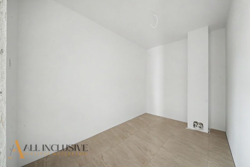 An empty room in a family house with white walls and a wooden-patterned floor.