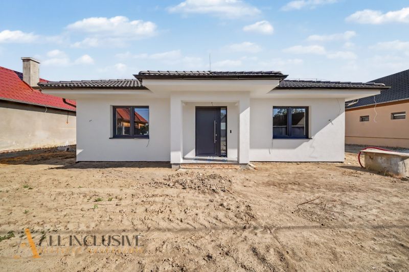 A family house in Tomášikovo with a white facade and a dark roof.