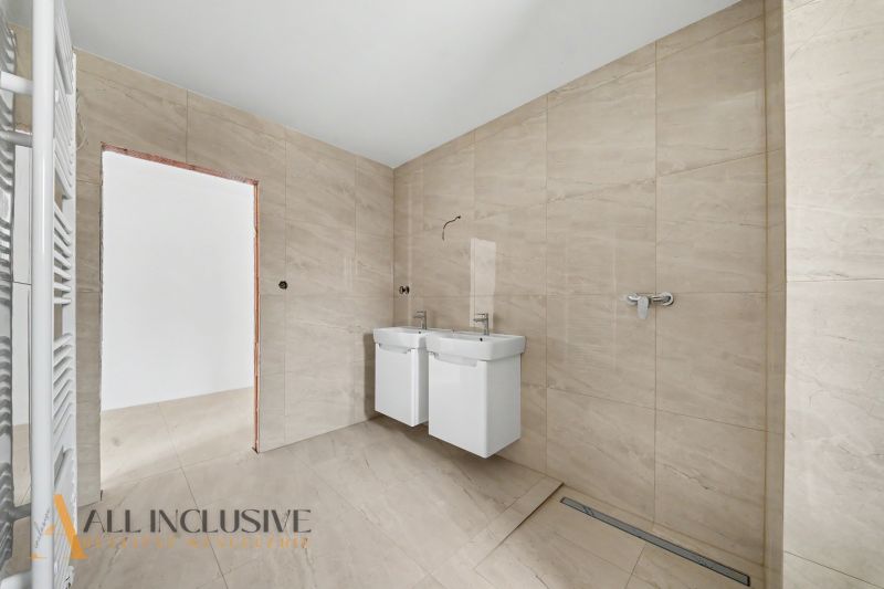 A bathroom in a family house with a double sink and beige tiles.