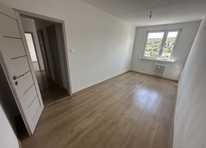A room in a 2-room apartment with a wooden decor floor and a view from the window.