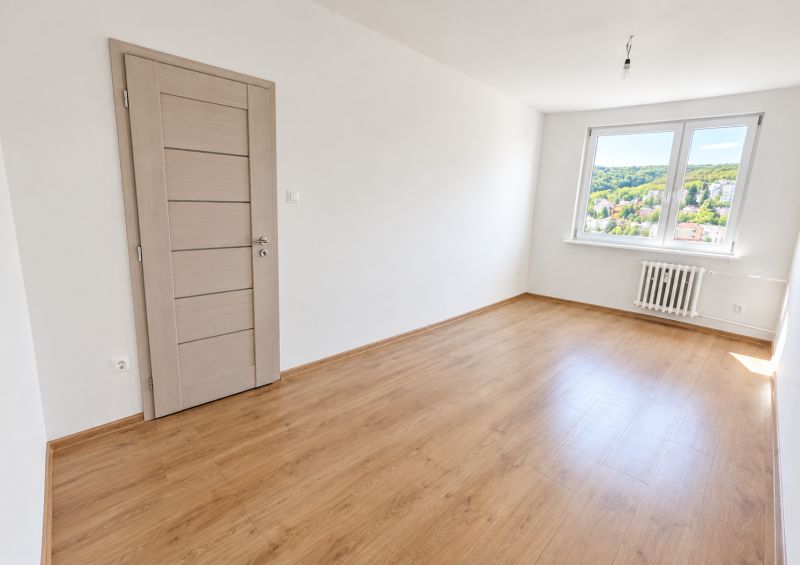 An empty room with a wooden decor floor in a 2-room apartment, light through the window.