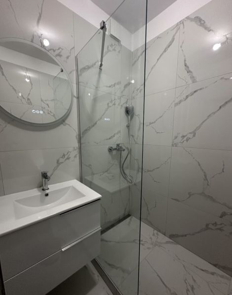A bathroom in a 2-room apartment with modern white tiles and a shower corner.