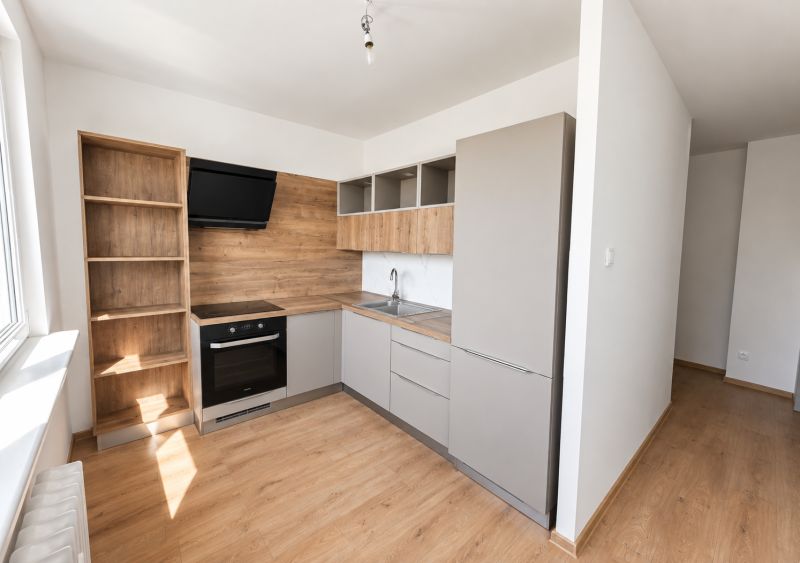 A kitchen in a 2-room apartment with a wooden decor floor and modern equipment.