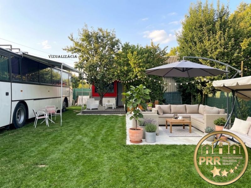 A yard with a bus, a couch, and a parasol by a cottage in Bánovce nad Bebravou.