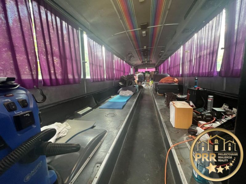 Interior of a cabin with purple curtains, wooden decor flooring, various items and equipment.