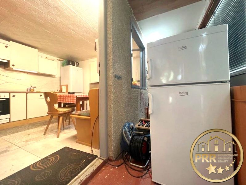 A cottage kitchen with a white refrigerator, wooden seating, and a dining table.