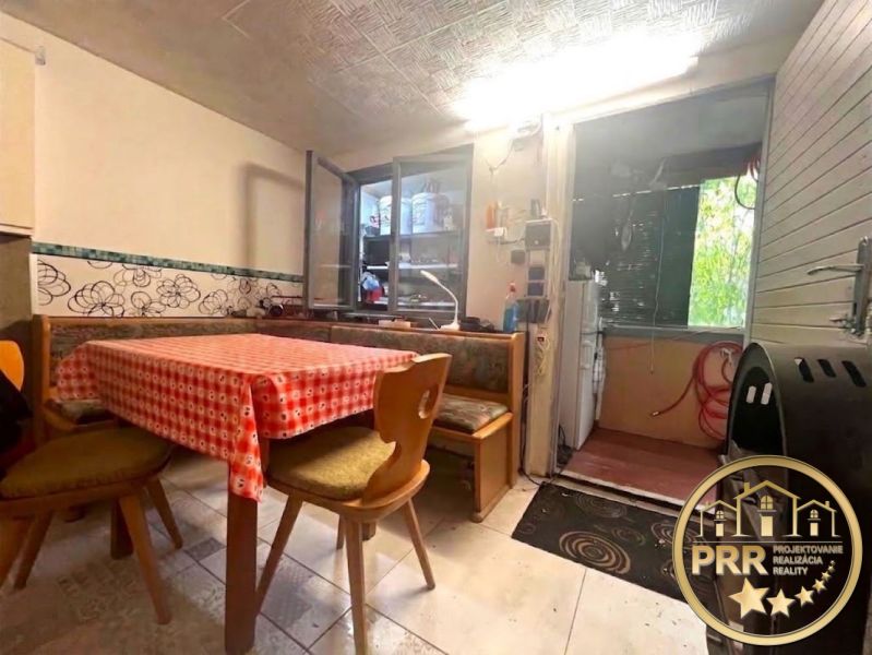 The interior of the cottage with a checkered tablecloth on the table and chairs with backrests.