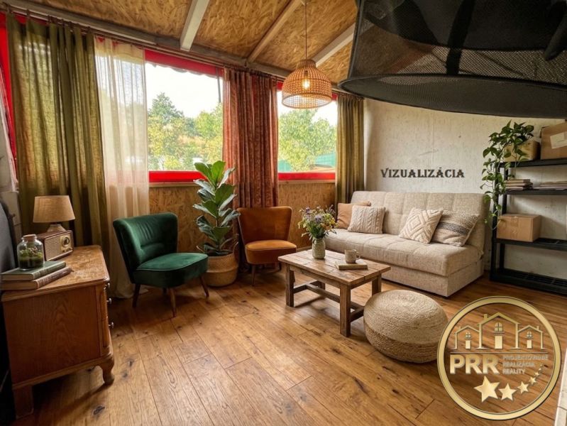 A cozy cabin interior with comfortable seating, plants, and a wood-patterned floor.