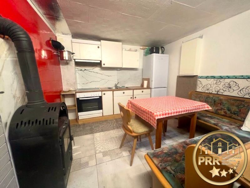 A kitchen in a cottage with appliances, a fireplace, a dining table, and a seating area.