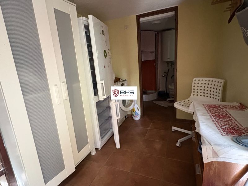 Kitchen area in the Cottage with a refrigerator, a cupboard, and a white armchair.