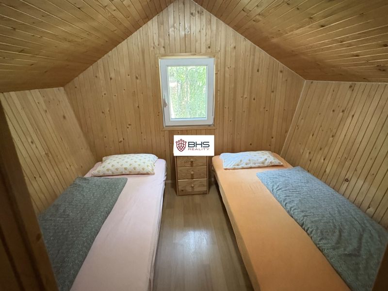 A wooden interior of a cabin with two beds and a window.