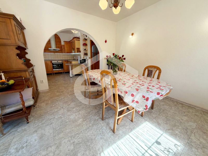 Dining area in a family house with wooden furniture and a floral tablecloth on the table.