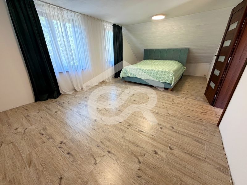 A bedroom with a double bed and a wooden decor floor in a family house.