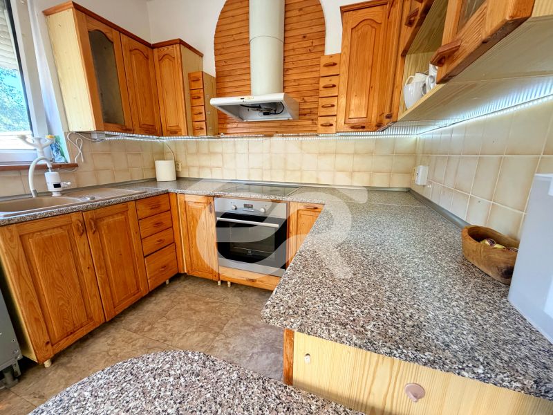 A kitchen in a family house with wooden cabinets, a sink, and a cooktop.