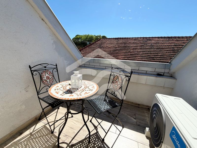 A balcony of a family house with a mosaic table against the backdrop of a sunny sky.