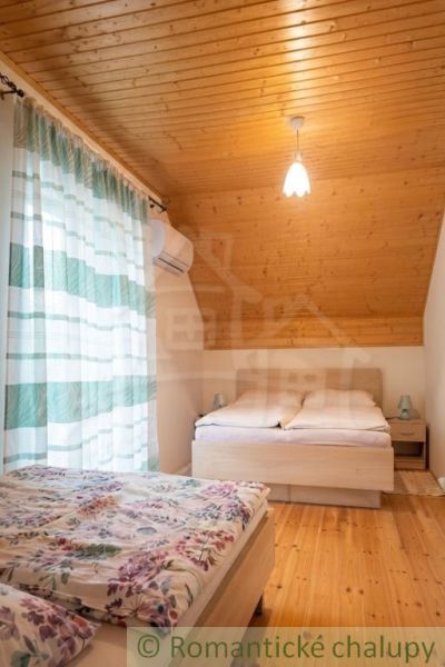 A bedroom in a cabin with two beds and curtains, floor with wooden decor.