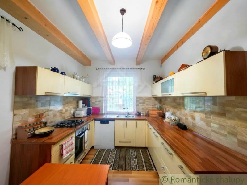 A kitchen in a cottage with wooden beams and a floor with a wooden decor.
