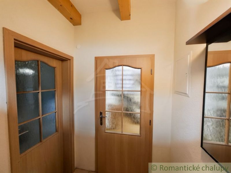 Interior doors with glass panels and wooden beams on the ceiling in the cottage.