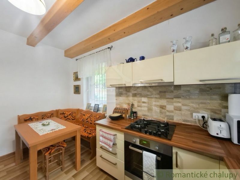 A kitchen in a cabin with wooden decor, a dining nook, and rustic details.