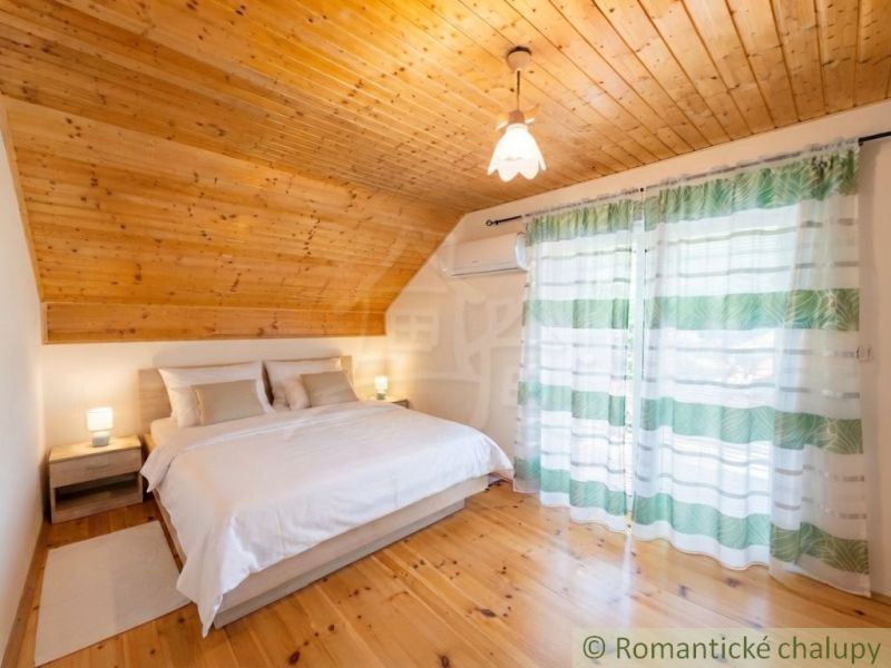 A bedroom in a cabin with a bed and a floor with a wooden decor, curtains with stripes.