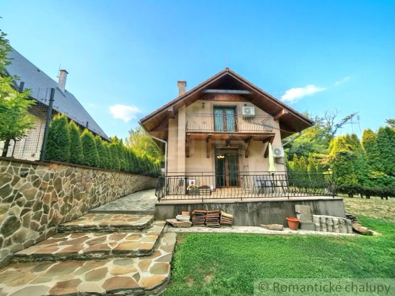 A cottage in Ružiná with brick walls, surrounded by greenery and a neat garden.
