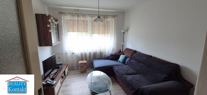 Living room in a family house with a couch, TV stand, and curtains.