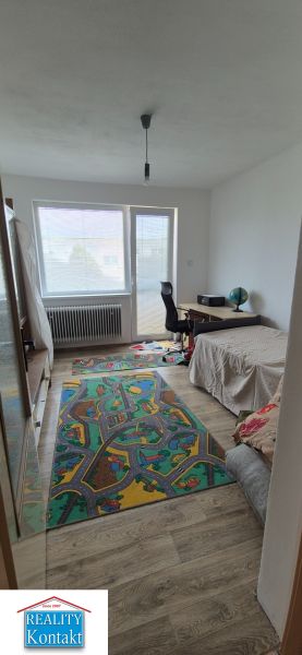 A room in a family house, with a bed, a desk, and a floor with a wooden decor.
