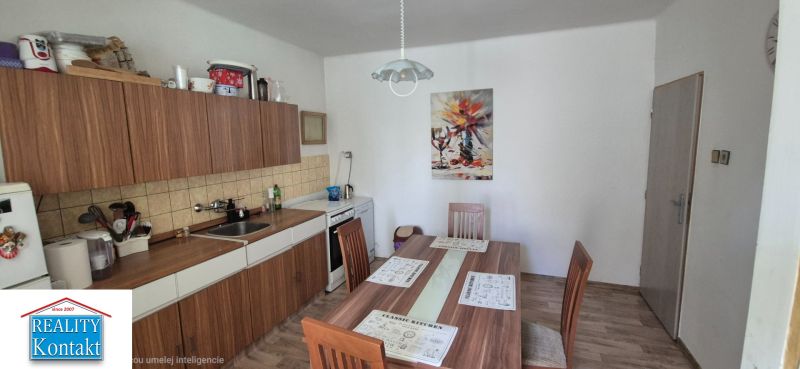 A kitchen in a family house with a dining table and kitchen unit, floor with wooden decor.