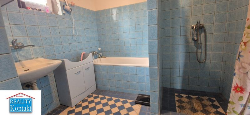 A bathroom in a family house with blue tiles, a bathtub, and a sink.