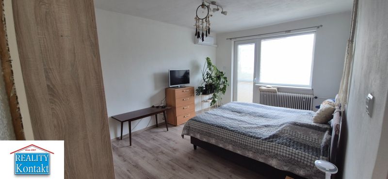 Bedroom in a family house with a TV, dresser, and wooden decor flooring.
