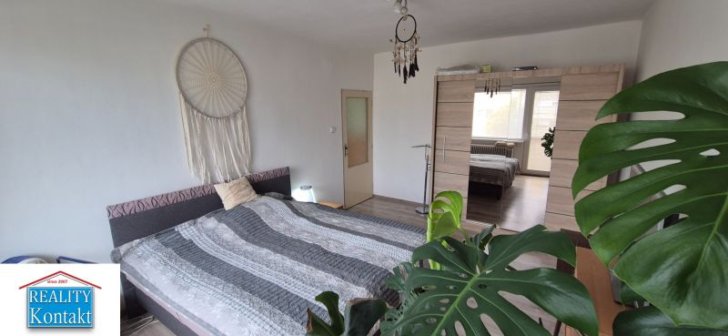 Bedroom in a family house with a double bed, wardrobe, and decorations in neutral tones.