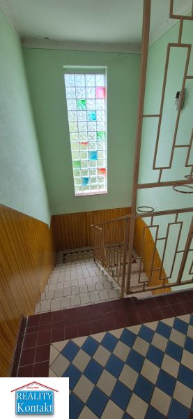 A staircase in a family house with a stained glass window and a tiled floor.