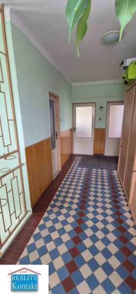 A hallway in a family house with patterned tiles and wooden wall paneling.
