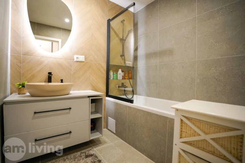 A bathroom with a bathtub and a mirror decorated with tiles in a 3-room apartment.