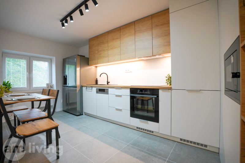 A kitchen in a 3-room apartment with a wooden decor and white cabinets.