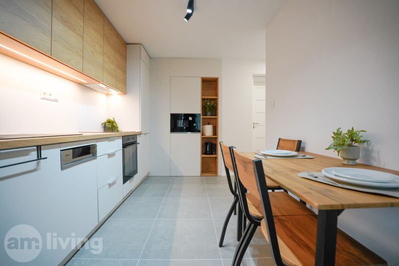 A kitchen in a 3-room apartment with wooden decor on the furniture and a dining table.