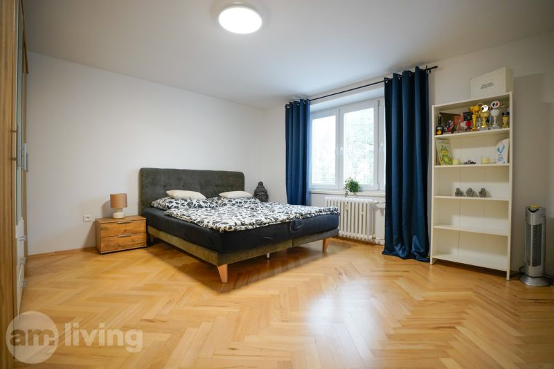 Bedroom in a 3-room apartment with wood-patterned flooring and blue curtains.