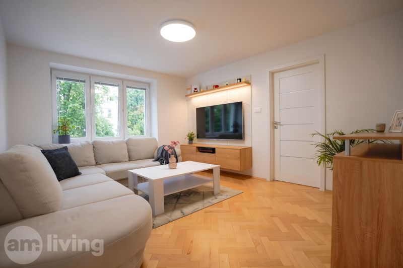 Living room in a 3-room apartment with a large sofa and a floor with a wooden decor.