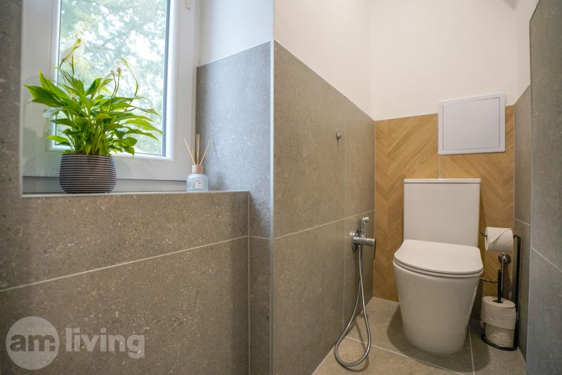 A bathroom in a 3-room apartment with a plant on the windowsill and walls with embossed tiles.