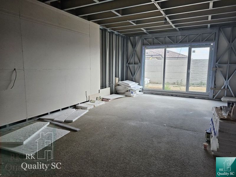 Interior of a family house under construction with a large window and building materials.