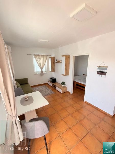 Living area of a studio apartment with a tiled floor and a dining table.