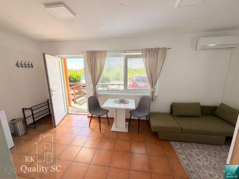 A studio apartment with a terracotta floor, a green sofa, and a table with chairs.