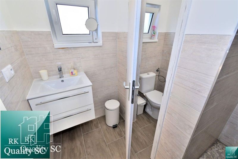 A bathroom in a cabin with a sink, toilet, and a floor with a wood decor.