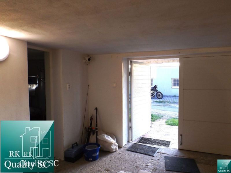 The garage of the cottage with open doors, from the view outside you can see a motorcycle.