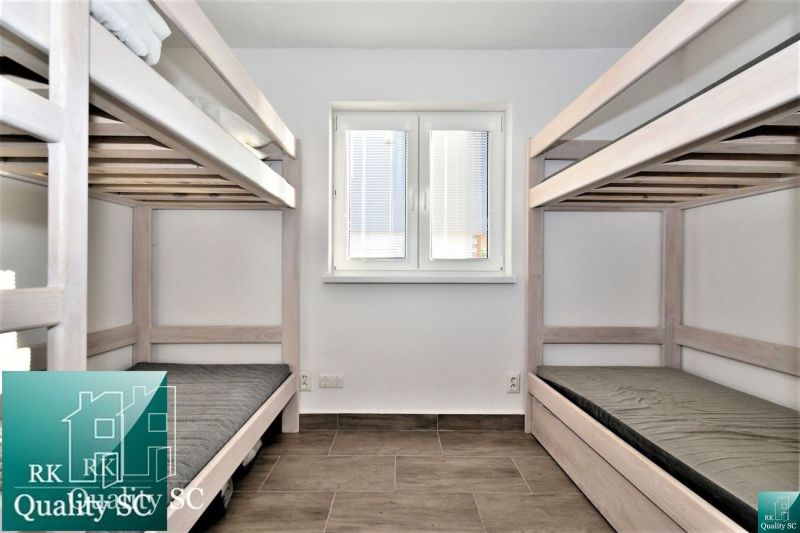 A cabin with two bunk beds, a wooden decor floor, a window in the middle.